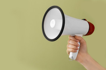 Female hand with megaphone on color background