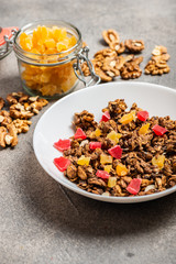 Granola with dried fruits in a white plate on a gray background. Macro.