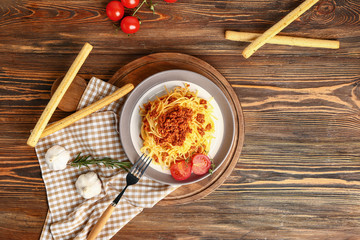Plate with tasty pasta bolognese on wooden table
