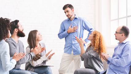 Fototapeta na wymiar Young man appreciating support at group therapy session in rehab