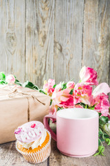 Obraz na płótnie Canvas Happy moms day greeting background. Mothers day sweet cupcakes, with gift boxes, coffee cappuccino cup, flowers. Wooden background copy space