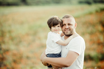 Fototapeta premium Beautiful portrait of a father with a son, a man is holding a boy on hands