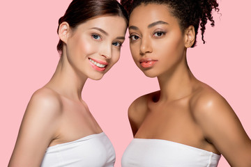 portrait of smiling multicultural girls with clean skin, isolated on pink