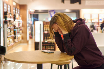 A woman sits at a table in sadness, upset.