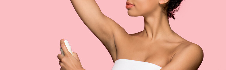 cropped view of african american girl using spray deodorant, isolated on pink, panoramic shot