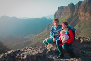 mom, dad and little baby daughter travel in mountains