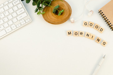 Good Morning wooden cubes text on a designer's Clean White office desk table with keyboard and supplies. Top view with copy space, flat lay