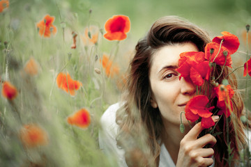 Naklejka premium Woman is covering a face with a poppies flower bouquet