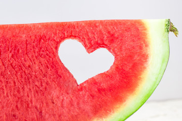 Fresh juicy watermelon slice with heart shape hole on white background. Valentines, love, summer concept