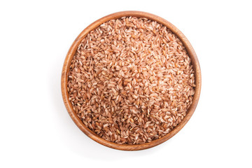 Wooden bowl with unpolished brown rice isolated on white background. Top view, close up.