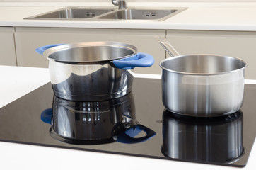 two stainless steel cooking pots on  induction cooking plate modern helper with low energy...