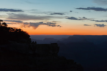 Man on a cliff, relaxing. Grand Canyon, sunset.