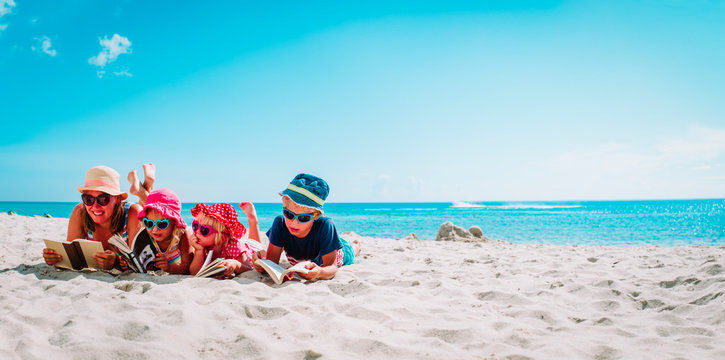 happy mother with kids reading books at beach, family on vacation