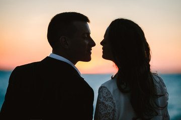 Happy smiled couple a moment before kiss in the picturesque evening dusk by the sea