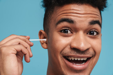 Photo of excited african american man using cotton swab and smiling