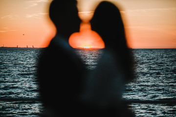 Silhouette of a romantic couple a moment before kiss on the breathtaking sunset by the sea