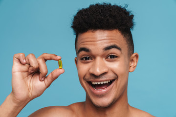 Photo of excited african american man showing vitamin capsule