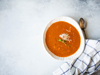 Fresh Tomato soup with cheese and fresh pea sprout in white rustic bowl on grey background. Copy space. top view