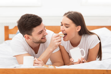 Loving Couple Feeding Each Other Having Morning Date In Bedroom