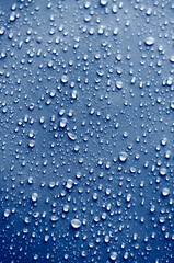 Round smooth beautiful clear drops of water of different sizes on a classic blue surface. Abstract background texture for design.