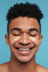 Photo of excited african american man with under eye patches smiling