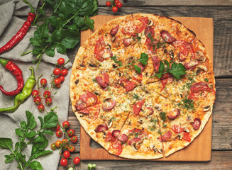 baked round pizza with smoked sausages, mushrooms, tomatoes