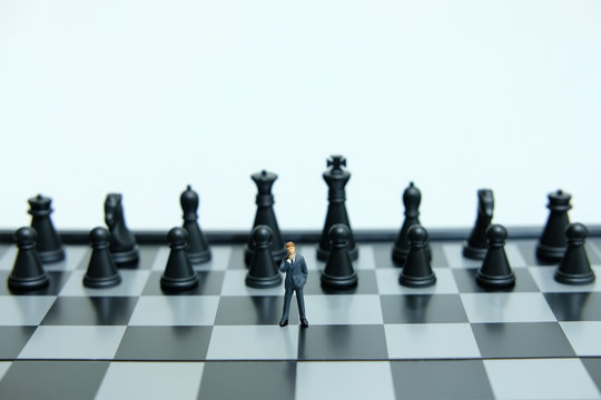 Business strategy conceptual photo - Miniature of businessman thinking in front black chess piece  