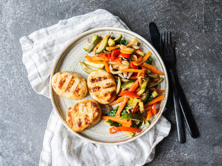 Turkey cutlets grill, vegetables steer fry on a plate on the table on dark background. Top view