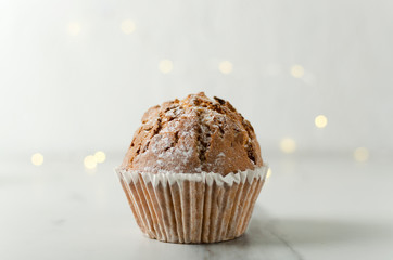 Closeup of one delicious cupcake on the bright table against lights and white wall