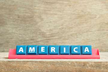 Tile letter on red rack in word america on wood background