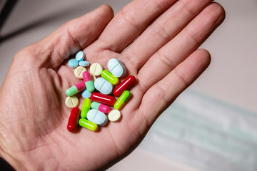 Colorful medicine in hand with mask and white background
