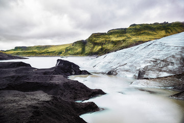 View of the Solheimajokull glacier in Iceland on a backgroung of a green hills