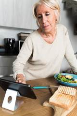 Woman chef scrolling on a tablet looking for an heathy receipt