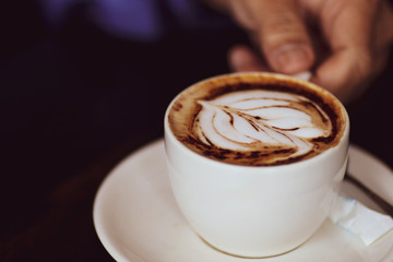 Latte coffee cup at coffee shop. Hand holding coffee cup.