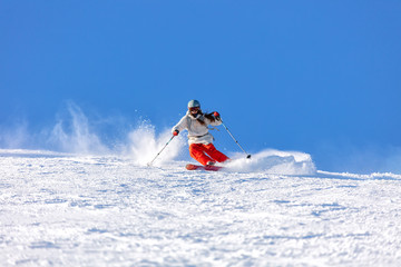 Girl On the Ski. a skier in a bright suit and outfit with long pigtails on her head rides on the...