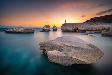 Beautiful sunset at the rocky beach near Limassol Cyprus with smooth water and white rocks standing out of water
