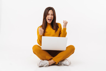 Image of woman holding laptop computer while sitting with legs crossed