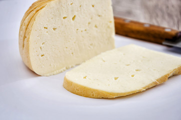 piece of smoked cheese and a knife on a wooden background. Gullsky, Ukrainian cheese.