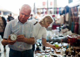 Loving senior family couple choosing vintage things on street market