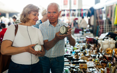 Loving mature couple buys alarm clock on flea market