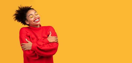 Lovely smiling afro woman embracing herself at studio