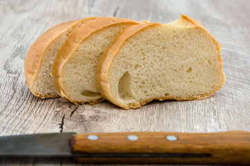 slices of loaf and knife on a wooden table.