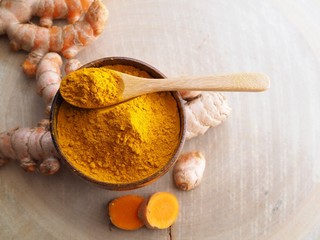 Above of turmeric powder in wooden bowl on wooden table.