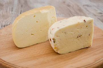 two pieces of hard cheese on a wooden background. Ukrainian cheese.