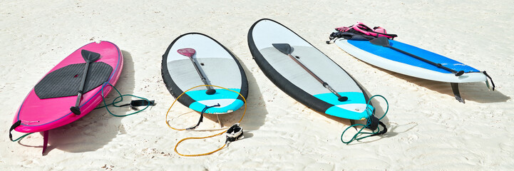 Panoramafoto van vier kleurrijke paddleboards om te liggen op het witte strand op Boracay, ze zijn te huur door toeristen tijdens het zomerseizoen