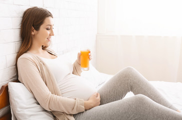 Obraz na płótnie Canvas Pregnant woman enjoying glass with freshly made orange juice