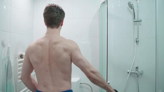 Male person working out while on toilette 4K. Medium shot of a nude male person in focus from behind in bathroom taking a leak and weight lifting at the same time.