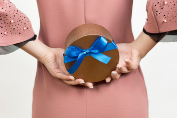 Girl holds a gift behind her back. A gift box in the hands of a girl a surprise for his young man.