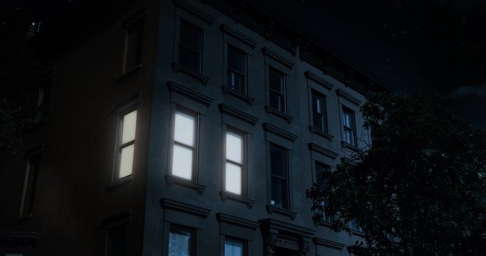 A nighttime exterior establishing shot of the upper floors of a typical Brooklyn brownstone residential home as a room lights up then turns off.	
