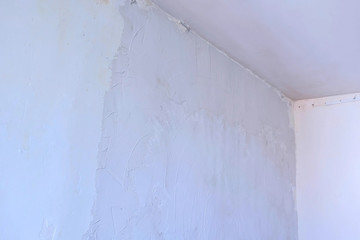 Putty wall aligning with plaster in room, renovation construction works and overhaul. Finishing repairing works. Texture of gray cement wet plaster and dry white wall. Plastering coating wall surface.